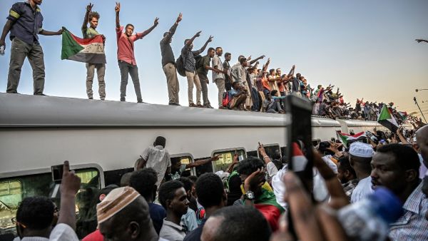 Sudanese protesters from the city of Atbara, flash the V-sign for victory and wave national flags atop a train, as it arrives at the Bahari station in Khartoum on April 23, 2019. (AFP/ File Photo)