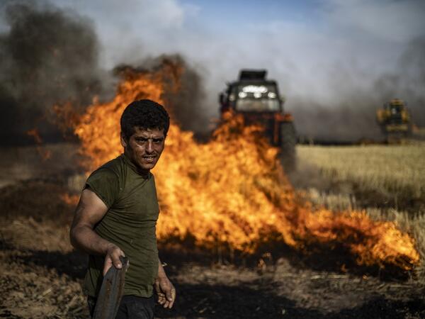 People battle a blaze next to an oil well in an agricultural field in the town of al-Qahtaniyah, in the Hasakeh province near the Syrian-Turkish border on June 10, 2019. Fires have erupted in various parts of Syria in recent weeks, with all sides blaming each other for starting them. Delil souleiman / AFP