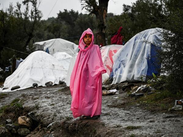 A young girl stands under the rain outside the refugee camp of Moria, on the island of Lesbos on November 26, 2019. Conditions remain difficult in the overcrowded Moria camp in Greece with winter fast approaching. The government announced on November 20it will shut down the three largest of its overcrowded migrant camps on islands facing Turkey, and replace them with new closed facilities with much larger capacity. ARIS MESSINIS / AFP