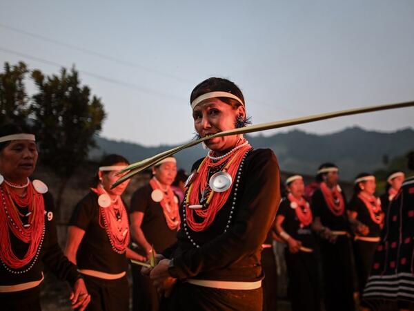 This photo taken on February 7, 2020 shows a Naga tribeswoman biting a coconut leaf at the end of an overnight ceremony to bless the harvest in Satpalaw Shaung village, Lahe township in Myanmar's Sagaing region. A haunting refrain pierces the night as the tribeswomen of the Gongwang Bonyo, among the most isolated people in Myanmar, dance around a campfire to bless the harvest ahead. Ye Aung THU / AFP