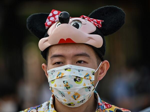A man fan wearing a face mask waits to enter the Disneyland amusement park in Shanghai on May 11, 2020. Disneyland Shanghai reopened on May 11 to the public after being closed since January due to the COVID-19 coronavirus outbreak. Hector RETAMAL / AFP