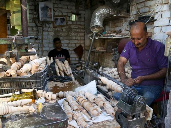 A carpenter shaves a piece of wood to make a narguileh (water pipe) at his workshop in Iraq's central holy city of Karbala on October 21, 2020. The business of strictly gender-separated cafes has carried on, despite the heavy health risks associated with smoking and a full-blown pandemic that has brought an average of 4,000 new coronavirus cases a day to Iraq. Mohammed SAWAF / AFP