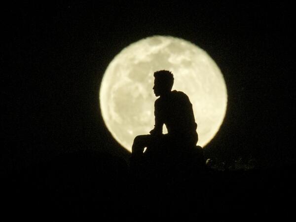 An Ehiopian man, who fled the Ethiopia's Tigray conflict as a refugee, watches the rising Moon on top of a hill at Um Raquba refugee camp in Gedaref, eastern Sudan, on December 1, 2020. Yasuyoshi CHIBA / AFP