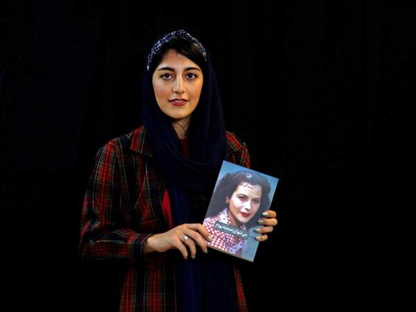 Employee Parisa Agha Mohammadi poses with a bestselling book of the Saless Publishing House in Iran's capital Tehran, on October 11, 2020. ATTA KENARE / AFP