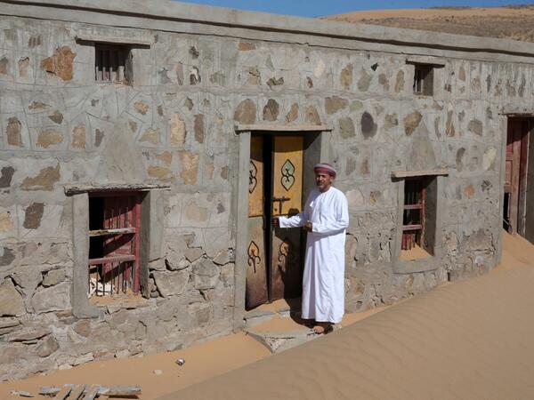 Mohammed al-Ghanbousi, a former inhabitant of Wadi al-Murr, stands next to his abandoned house in the Omani village, about 400 kms (250 miles) southwest of the capital Muscat, on December 31, 2020. Encroaching desert sands have left little evidence that Wadi al-Murr ever existed, but former inhabitants, while resigned to its destruction, are trying to preserve its memory. MOHAMMED MAHJOUB / AFP