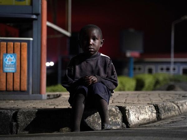 A lost child sits on a curb as Congolese people flee from Goma, Democratic Republic of Congo (DRC), after the Nyiragongo volcano erupted, at the border point known as "Petite Barriere" in Gisenyi, Rwanda, on May 23, 2021. The government of the Democratic Republic of Congo has ordered the evacuation of the eastern city of Goma after the eruption of Mount Nyiragongo overlooking the border city. The lava reached the city's airport early Sunday, with an official from Virunga National Park