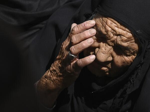 An elderly woman reacts as she sits in a queue along with others to submit their passport applications at an office in Kabul on July 25, 2021. Dozens begin lining up at the passport office in Kabul before dawn most days, and by eight in the morning the queue already stretches for a good hundred metres. 