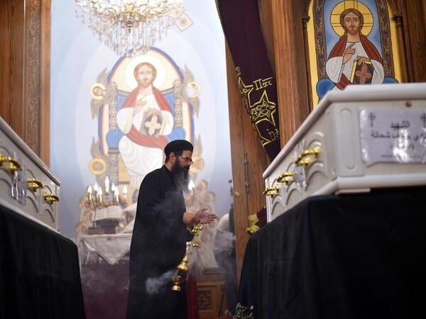 An Coptic priest blesses the coffins of victims, killed in an attack a day earlier, during an early morning ceremony at the Prince Tadros church in Egypt's southern Minya province, on November 3, 2018. 
MOHAMED EL-SHAHED / AFP