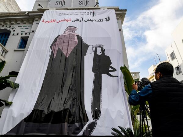 This picture taken on November 26, 2018 shows a giant banner hanging at the headquarters of Tunisia's Journalists Union in the capital Tunis depicting a cartoon of Saudi Crown Prince Mohammed bin Salman holding a chainsaw with a caption above reading in Arabic "no to the desecration of Tunisia, the land of the revolution". 
FETHI BELAID / AFP