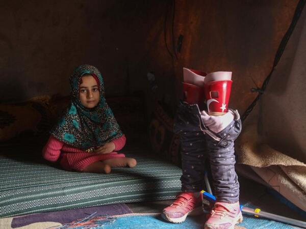 Syrian Maya Merhi poses for a picture next to her prosthetic legs that are decorated with the Turkish flag inside a tent at the Internally Displaced Persons (IDP) camp of Serjilla in northwestern Syria. 
Aaref WATAD / AFP