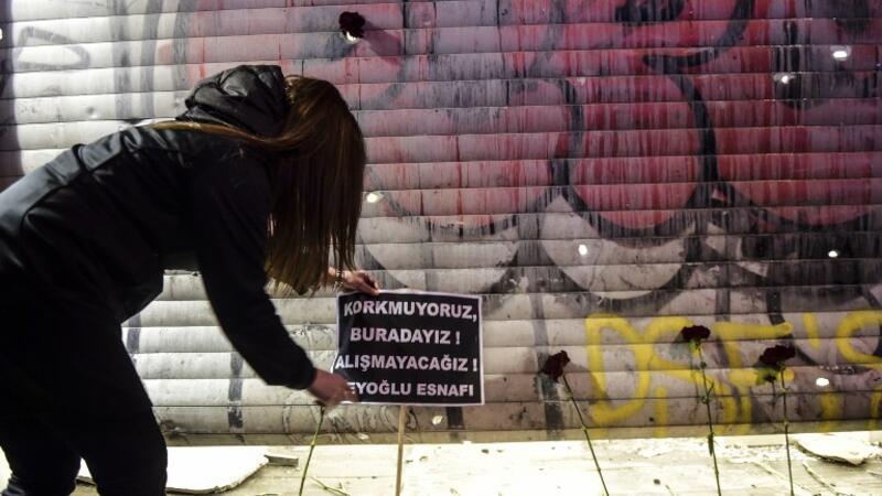 A woman puts a placard reading in Turkish "We are not afraid, we are here, we won't adjust" at the site of a blast on Istiklal Street, a major shopping and tourist district, in central Istanbul on March 19, 2016. (AFP/Bulent Kilic)