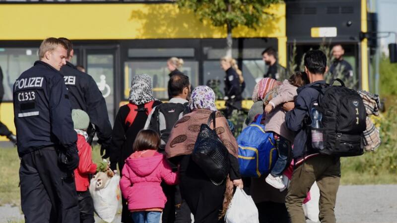 Police officers accompany migrants to a bus after they arrive at the railway station in Schoenefeld near Berlin, eastern Germany, on Sept. 8, 2015. (AFP/Bernd Settink)
