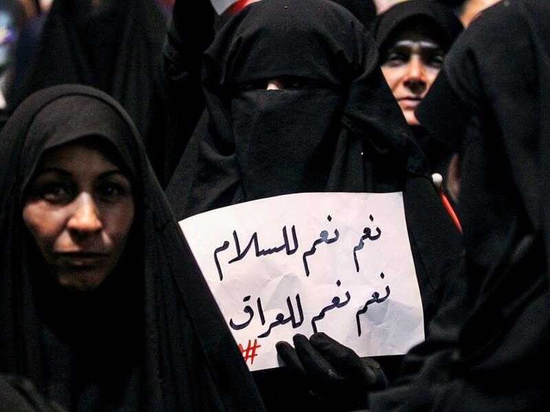 An Iraqi woman holds up a sign reading in Arabic "yes, yes to peace, yes, yes to Iraq" as she demonstrates with other followers of Shiite Muslim cleric Moqtada al-Sadr in the capital Baghdad's central Tahrir Square late on May 24, 2019, against involvement in any conflict between Iran and the United States.  AHMAD AL-RUBAYE / AFP