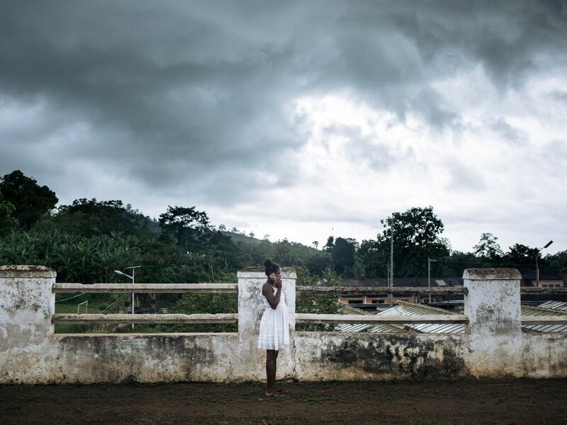 An inhabitant of the roca Agostinho Neto, an abandoned cocoa plantation of Sao Tome and Principe, phones on the paved road of the roca, on May 29, 2019.  Alexis HUGUET / AFP
