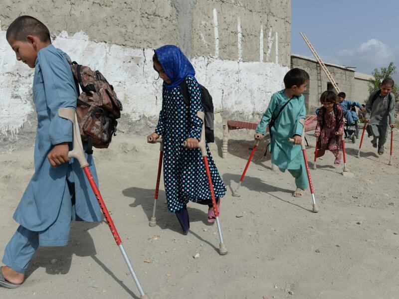 In this photograph taken on September 8, 2018, Afghan disabled children belonging to Hamisha Gul family who lost their legs following unexploded rocket explosion, walk outside their house after a class in Khogyani the district of Nangarhar province. NOORULLAH SHIRZADA / AFP