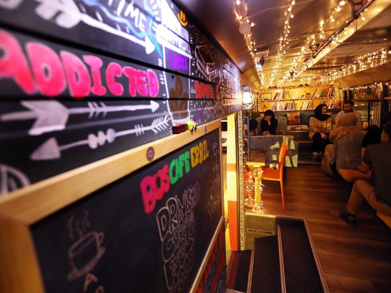 People have a drink at "The Bus Cafe Erbil" in Arbil, the capital of Iraq's Kurdish autonomous region, on June 7, 2019, on the long weekend of the Eid al-Fitr holiday which marks the end of the Muslim holy month of Ramadan.  SAFIN HAMED / AFP