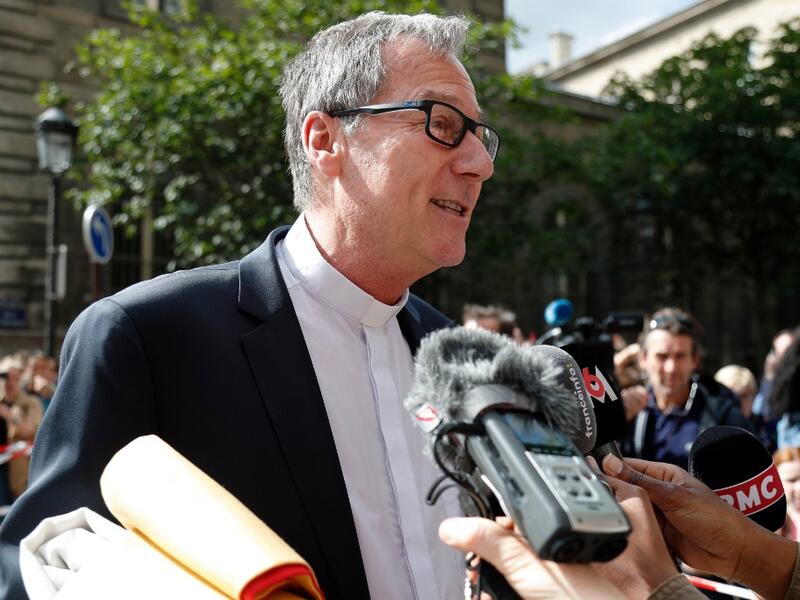 A member of the church answers journalists questions prior to entering the Notre-Dame de Paris cathedral, to take part in a mass, the first since the fire that destroyed the cathedral's roof on April 15, in Paris on June 15, 2019. Zakaria ABDELKAFI / AFP