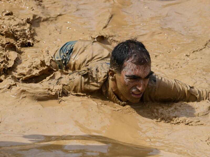 A runner crawls in mud as he takes part in the Mud Day, a 13km race with obstacles in Beynes, near Paris on June 16, 2019.  ALAIN JOCARD / AFP