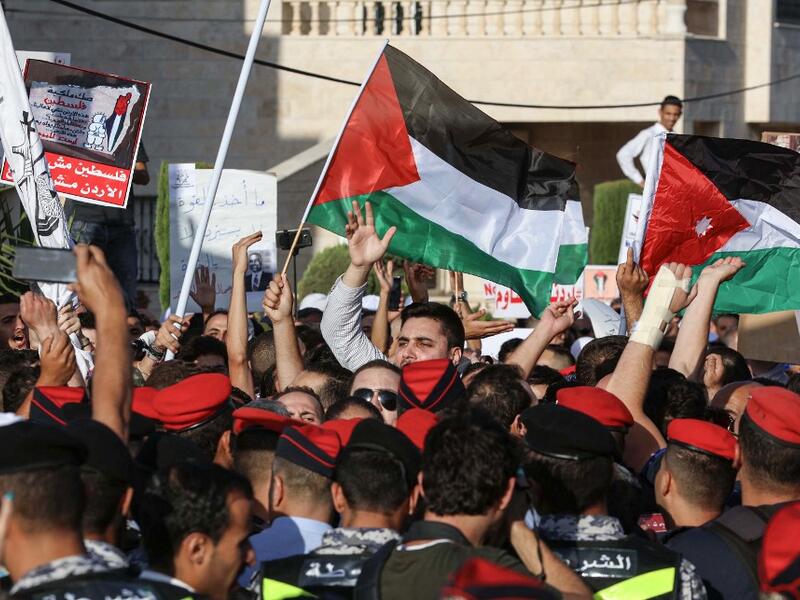 Protesters wave Palestinian (C) and Jordanian (R) flags as they chant slogans during the "March of Anger" demonstration leading to the US Embassy in the Jordanian capital Amman on June 21, 2019, against the US President's "Deal of the Century" and the US-led Middle East economic conference in Bahrain.  Khalil MAZRAAWI / AFP