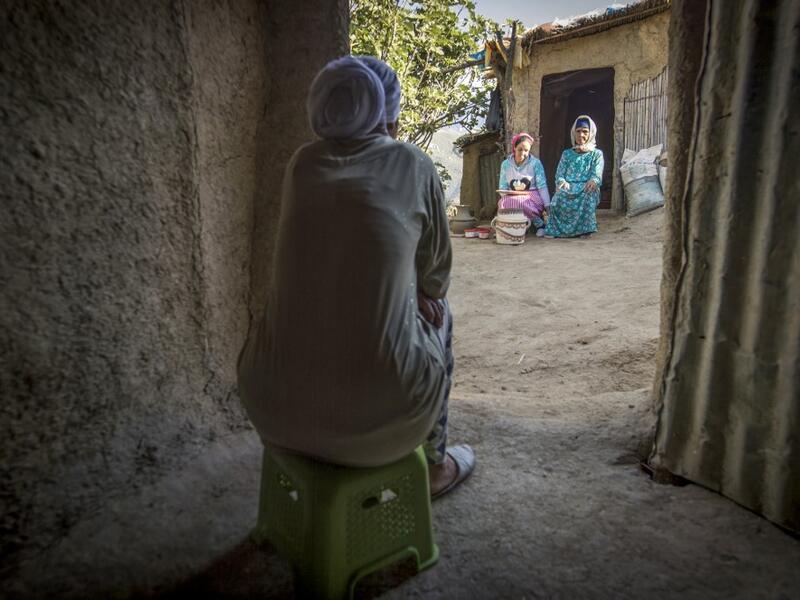 A neighbour watches as Moroccan potter Houda Oumal (C) sitting next to her mother Fatima Harama (R) paints with natural pigments on one of her pieces of pottery, near the village of Ourtzagh in the region of Taounate on june 11, 2019. FADEL SENNA / AFP