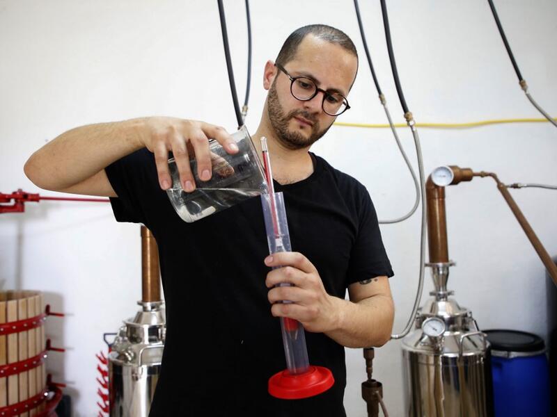 Palestinian distiller Nader Muaddi uses an alcoholometer to measure the amount of alcohol in his Arak in the West Bank village of Beit Jala, near Bethlehem, on June 16, 2019. In his basement, distiller Muaddi made fewer than 500 bottles of liquor last year, but it is earning global acclaim and reviving interest in the Palestinian alcohol sector. On the outskirts of the city famed for Jesus's birth, the 35-year-old illustrates the handcrafted way he makes Arak, an anise-flavoured drink popular in the Middle 