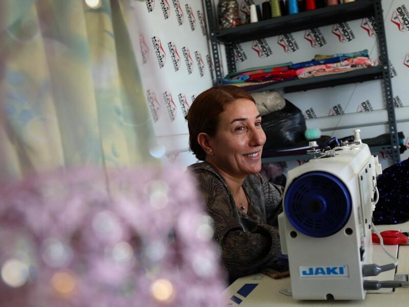 Iraq's Yazidi seamstress Shirin Ghaliyeh, 39, smiles while working at her shop in the Khonke camp for displaced persons in northwestern Iraq on June 24, 2019. SAFIN HAMED / AFP