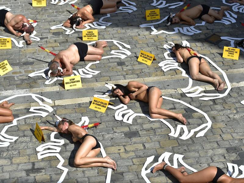 Pro-animal rights activists lie on the ground during a protest against bullfighting and bull-running called by the People for the Ethical Treatment of Animals (PETA) pro-animal group on the eve of the San Fermin festivities in the Northern Spanish city of Pamplona on July 5, 2019.  ANDER GILLENEA / AFP