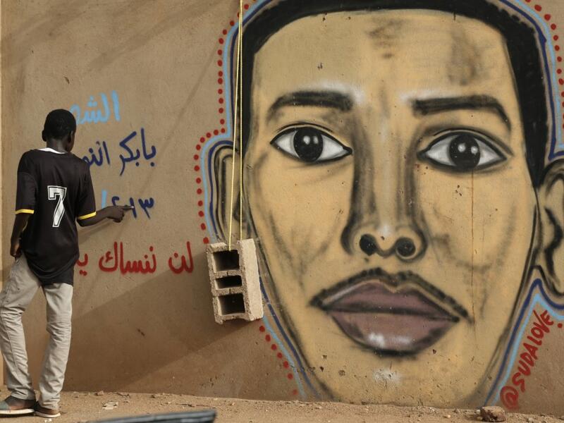A man walks past the mural painting of Babikir Anwar on the wall of the family home in the neighbourhood of Shambat, in the Sudanese capital Khartoum.  ASHRAF SHAZLY / AFP