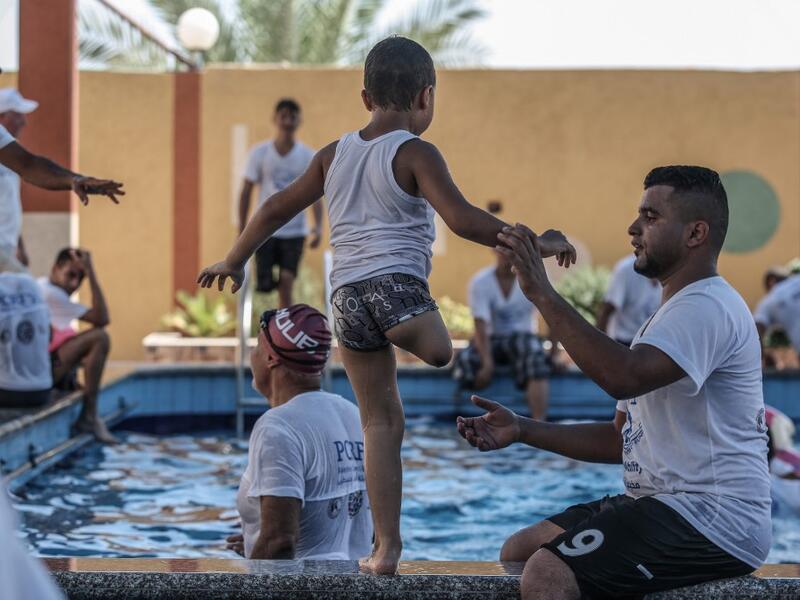 A trainer helps a Palestinian amputee child during a summer camp origanized by the Palestinian Children's Relief Fund (PCRF) in the town of Khan Yunis in the southern Gaza strip on August 3, 2019.  SAID KHATIB / AFP