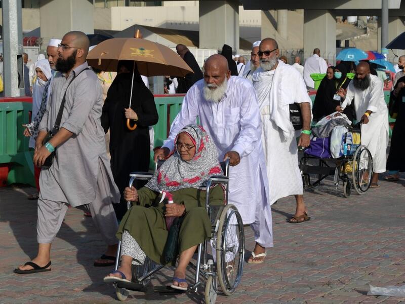 A Muslim worshipper seated in a wheelchair is pushed as she and her escort arrive in Mina to throw pebbles as part of the symbolic al-A'qabah. (AFP)