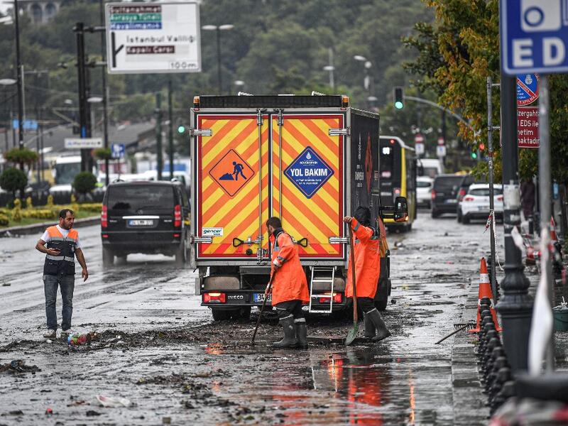 Municipality employees work on the road in Eminonu district, Istanbul, after a heavy rainfall, on August 17, 2019. Turkey's mega city Istanbul was lashed by a heavy rainstorm on August 17, killing a homeless man and leaving parts of the historic Grand Bazaar flooded.  Ozan KOSE / AFP