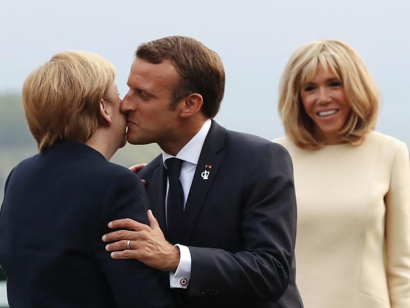 French President Emmanuel Macron (C) welcomes German Chancellor Angela Merkel with a kiss past his wife Brigitte Macron at the Biarritz lighthouse, southwestern France, ahead of a working dinner on August 24, 2019. Francois Mori / POOL / AFP