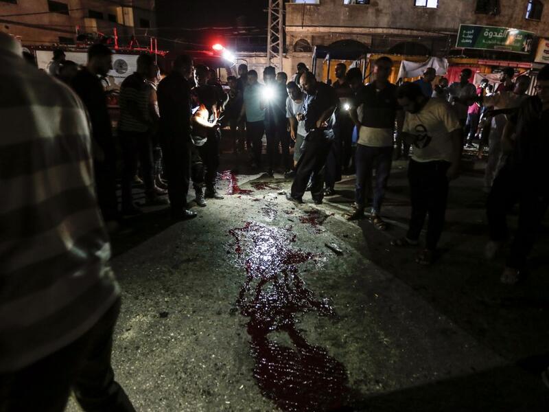 Palestinians look at blood stains on the ground after an unknown explosion near a police checkpoint in Gaza City on August 27, (AFP/ File Photo)