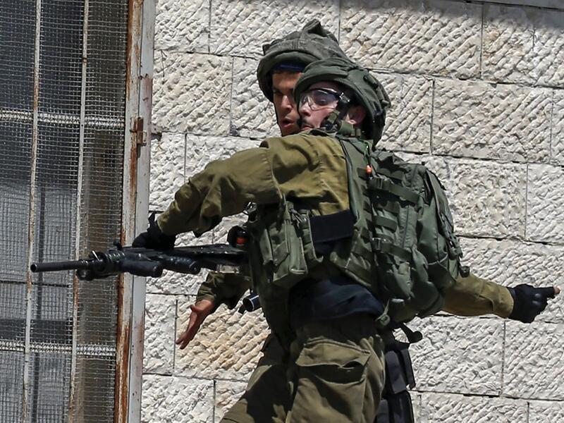 An Israeli soldier throws a stun grenade during clashes (AFP)