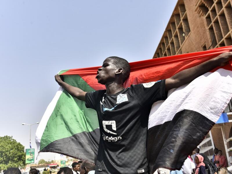 A Sudanese man spreads a national flag in Omdurman as he takes part in a rally in solidarity with Ahmed al-Kheir, a young Sudanese who died in custody after his arrest in January on allegations of organising anti-Bashir protests, on August 28, 2019. (AFP/ File Photo)