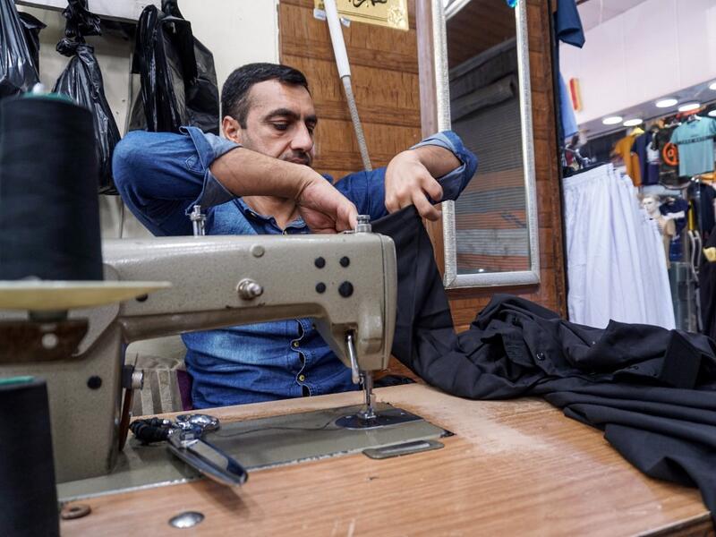 A man sews together black garbs to be sold to Shiite Muslim pilgrims amidst preparations ahead of the Shiite religious mourning period of Ashura, in the central Iraqi holy shrine city of Najaf on August 31, 2019.  Haidar HAMDANI / AFP