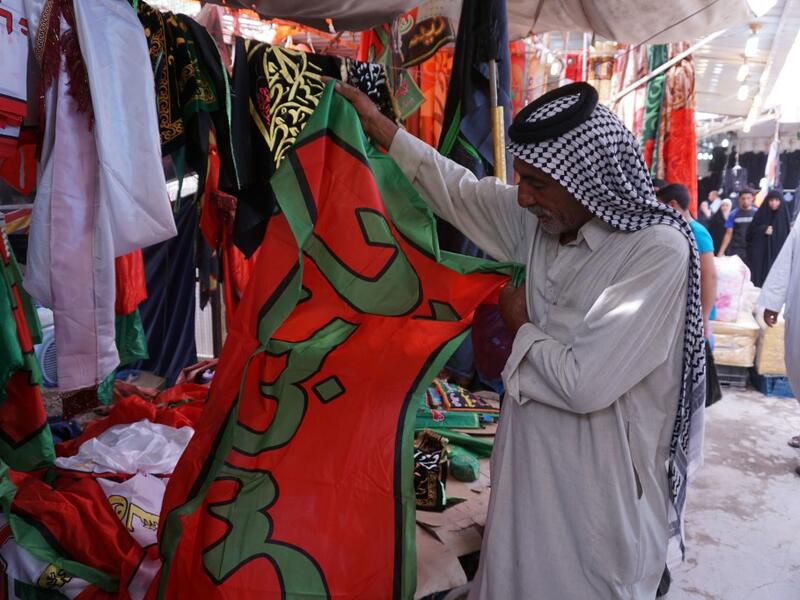 A man holds up a banner reading in Arabic "O Abbas" referring to the Shiite Muslim Imam Abbas ibn Ali, grandson of the prophet Mohammed, sold by a peddlar amidst preparations ahead of the Shiite Muslim religious mourning period of Ashura, in the central Iraqi holy shrine city of Najaf on August 31, 2019.  Haidar HAMDANI / AFP