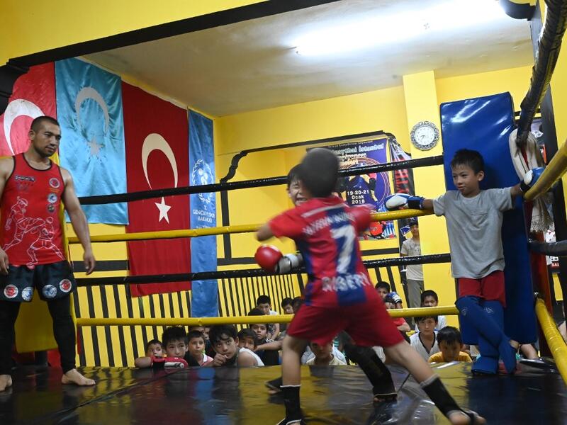 In this photograph taken on August 29, 2019, children from Muslim Uighur minority take part in a training boxing match as a trainer and children watch in Istanbul. BULENT KILIC / AFP