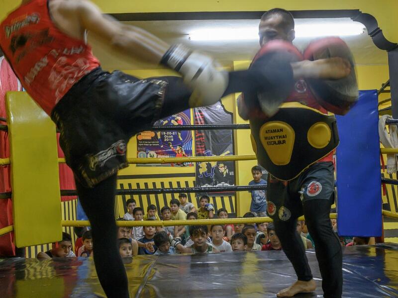 In this photograph taken on August 29, 2019, Muay Thai boxer practices with a trainer as children from Muslim Uighur minority watch in Istanbul. BULENT KILIC / AFP