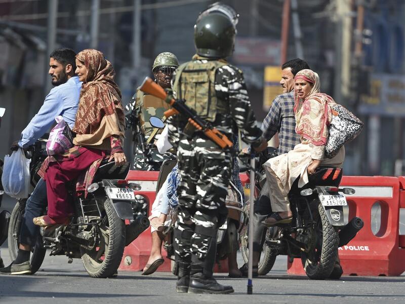 Indian paramilitary troopers stop Indian Kashmiri motorcyclists during a strict curfew in Lal Chowk (AFP)