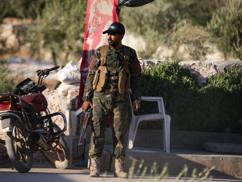 A Turkish-backed Syrian fighter stands guard on the outskirts of Syria's northern town (AFP)