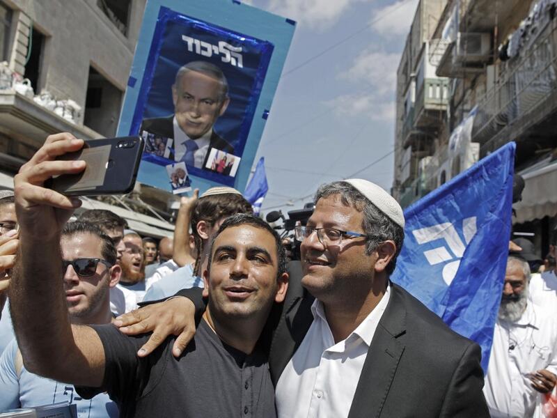 Leader of the far right 'Otzma Yehudit' (Jewish power) party Itamar Ben-Gvir poses for a selfie with a supporter as he campaigns at the Mahane Yehuda Market in Jerusalem on September 13, 2019. MENAHEM KAHANA / AFP