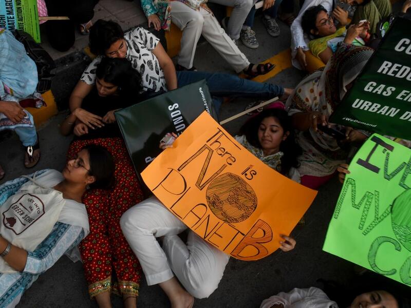 Youths hold placards as lie on the ground during a climate strike to protest against governmental inaction towards climate breakdown and environmental pollution, part of demonstrations being held worldwide in a movement dubbed "Fridays for Future", in Karachi on September 20, 2019. ASIF HASSAN / AFP