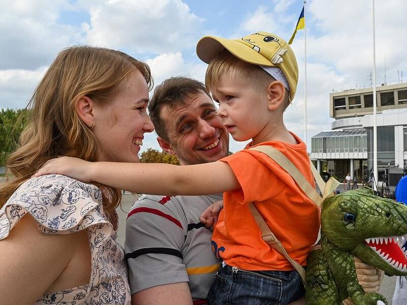 A former prisoner hugs his wife and child after he disembarked from a plane in Ukraine. Relations deteriorated between the two countries in 2014 (AFP)