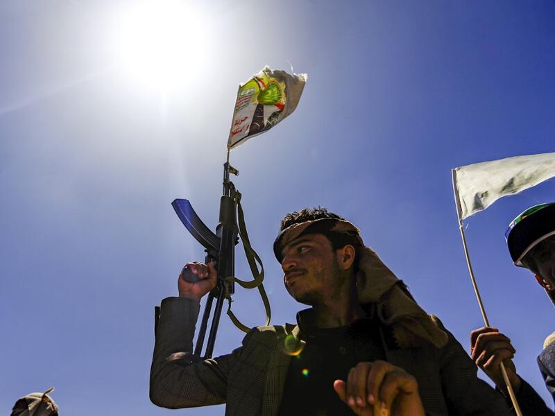 A Yemeni man holds up a Kalashnikov assault rifle with a flag sticking from its barrel showing a picture of the Huthi rebel leader Abdulmalik al-Huthi, during a tribal meeting in the Huthi rebel-held capital Sanaa on September 21, 2019, as tribesmen donate rations and funds to fighters loyal to the Huthis along the fronts. (Mohammed HUWAIS / AFP)
