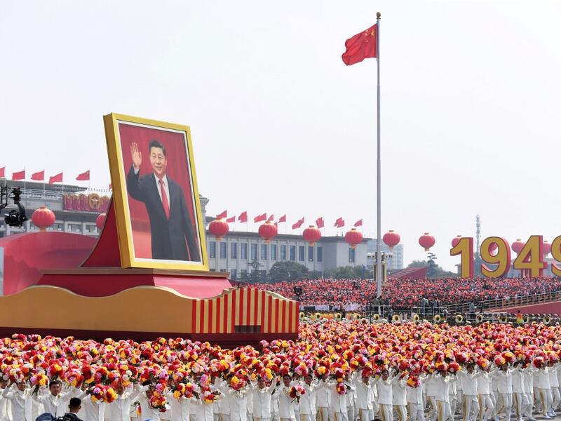 A float with a giant portrait of China's President Xi Jinping passes by Tiananmen Square during the National Day parade in Beijing on October 1, 2019, to mark the 70th anniversary of the founding of the People's Republic of China. GREG BAKER / AFP