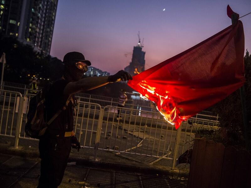 A protester sets fire to the Chinese national flag in the Sha Tin district of Hong Kong on October 1, 2019, as violent demonstrations take place in the streets of the city on the National Day holiday to mark the 70th anniversary of communist China's founding. ISAAC LAWRENCE / AFP