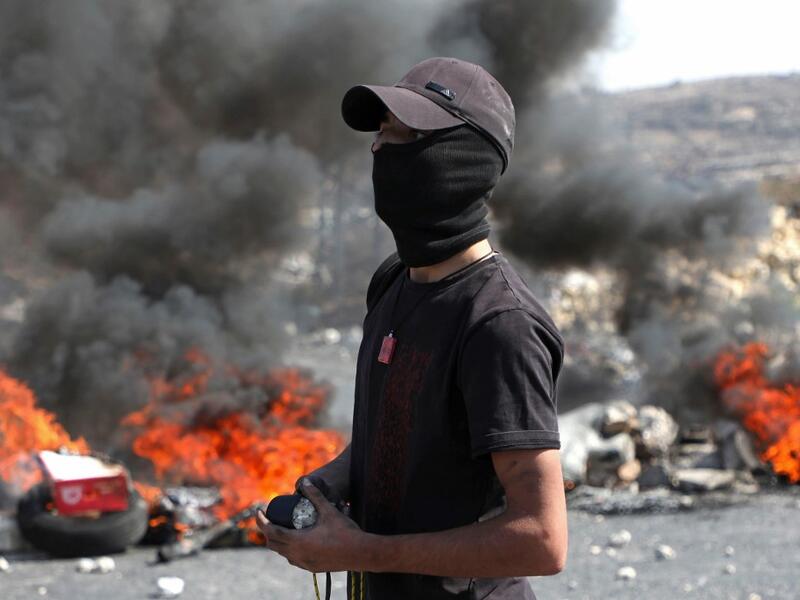 A Palestinian protester watches during clashes with Israeli security forces at the entrance of the West Bank city of Ramallah close to the Jewish settlement of Beit El, following a demonstration to show solidarity with Palestinian prisoners held in Israeli jails on October 1, 2019. (ABBAS MOMANI / AFP)