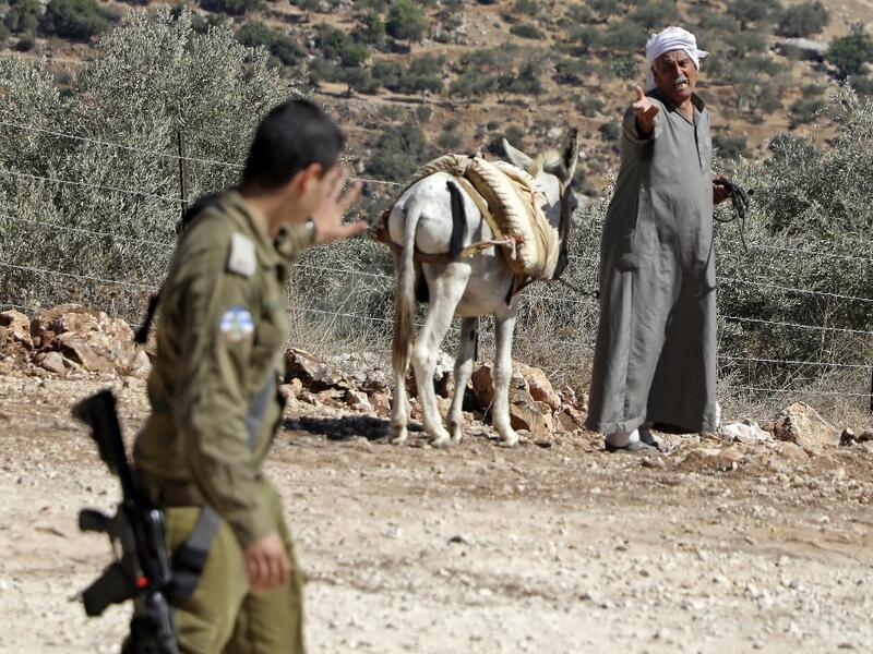 A Palestinian farmer reacts as an Israeli soldier walks past him during a demonstration against the closure of agricultural roads leading to the olive fields in the village of Kafr Thulth, east of Qalqilya in the occupied West Bank, on October 4, 2019. (Jaafar ASHTIYEH / AFP)