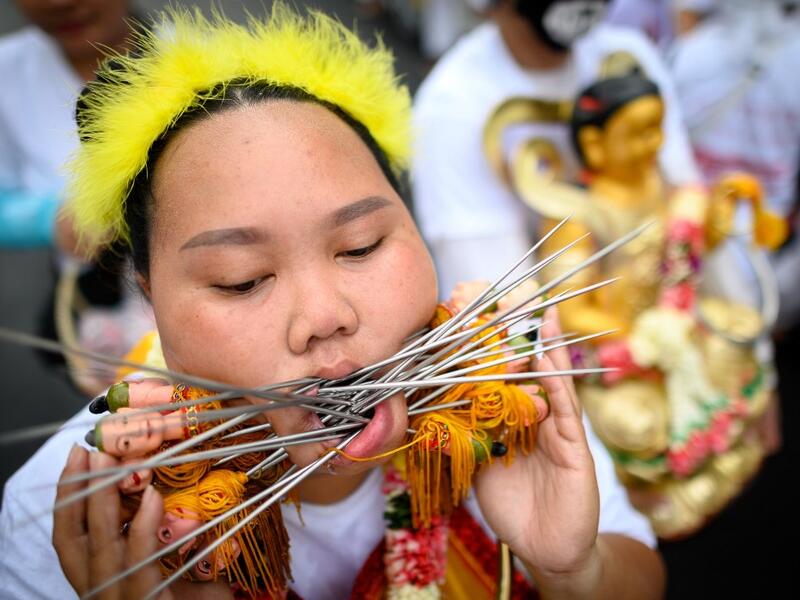 A devotee of a Chinese shrine with multiple skewers pierced through her cheeks takes part in a procession during the annual Vegetarian Festival in Phuket on October 5, 2019. Mladen ANTONOV / AFP